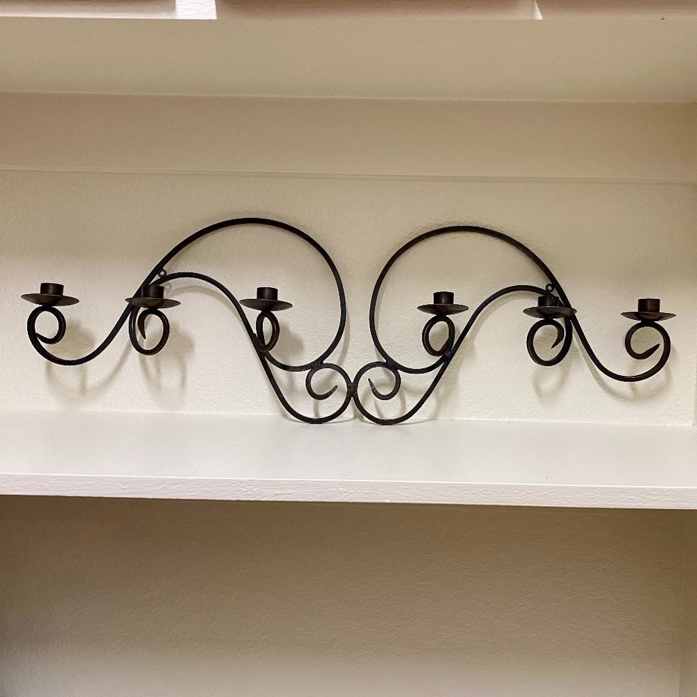 Wall mounted wrought iron candelabra for taper candles.